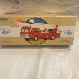 Puede incluir: Un camión de bomberos rojo y blanco con una escalera y un tanque de agua. El camión está etiquetado como "Simon Dennis Plataforma hidráulica" y "West Glamorgan Fire Brigade". El camión es un modelo del 20º aniversario.