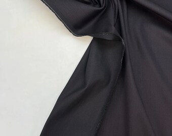 May include: Black fabric with a smooth, slightly textured surface. The fabric is folded and draped, showing its drape and texture.