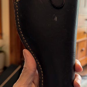 Peut inclure: Un étui en cuir marron foncé avec une couture cousue et une fermeture à bouton-pression. L'étui a un aspect usé et vintage, avec un intérieur marron clair contrastant et une sangle en cuir.