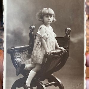 Darling 1930er Sepia Ton RPPC Echt Foto Postkarte des Kindes im süßen Kleid auf wunderschönem Savonarola Stuhl Rue Regence Liege, Belgien