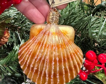Adorno navideño de cristal con forma de concha de vieira, típico de la Navidad del Viejo Mundo.