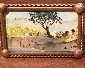 Op de afbeelding: Kleine ingelijste landschapsschilderij met een boom en een waterpartij. Het schilderij zit in een goudkleurige lijst met een gedraaid touwontwerp. Het schilderij is gesigneerd "An. 197".