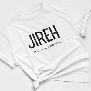 Può includere: Maglietta bianca con testo nero che dice "JIREH YOU ARE ENOUGH".