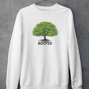 May include: White sweatshirt with a green tree graphic and the word "ROOTED" printed below it.