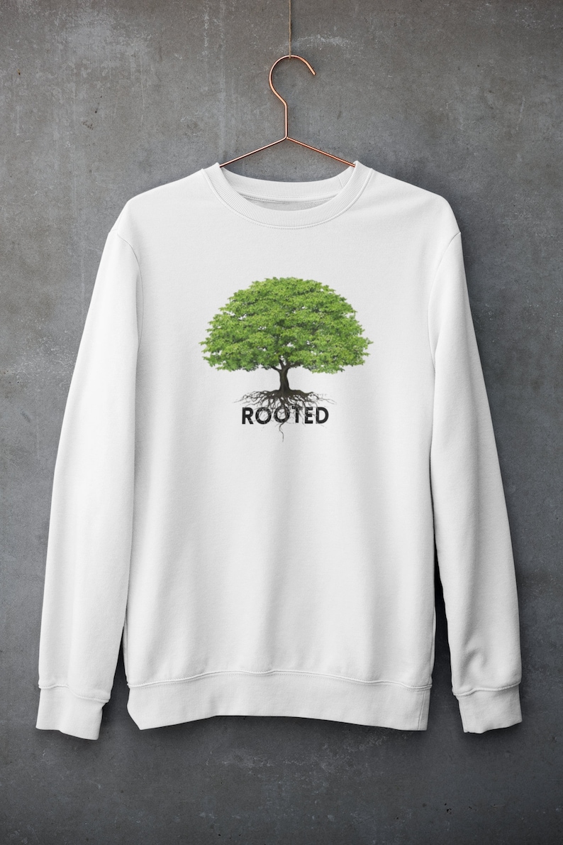 May include: White sweatshirt with a green tree graphic and the word "ROOTED" printed below it.