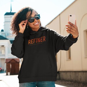 May include: A black hoodie with a large orange and red graphic that says "REFINER" with the text "CLEAN MY HANDS, PURIFY MY HEART" underneath.