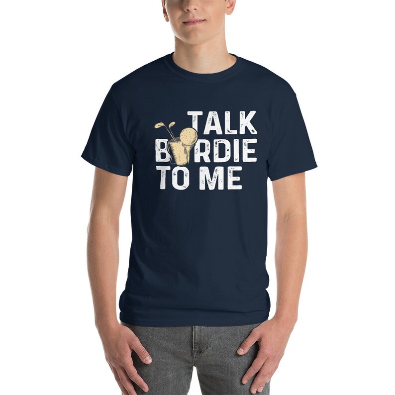 Op de afbeelding: Een marineblauw t-shirt met een witte afbeelding waarop "Talk Birdie To Me" staat en een cartoonafbeelding van een golfbal in een cocktailglas.