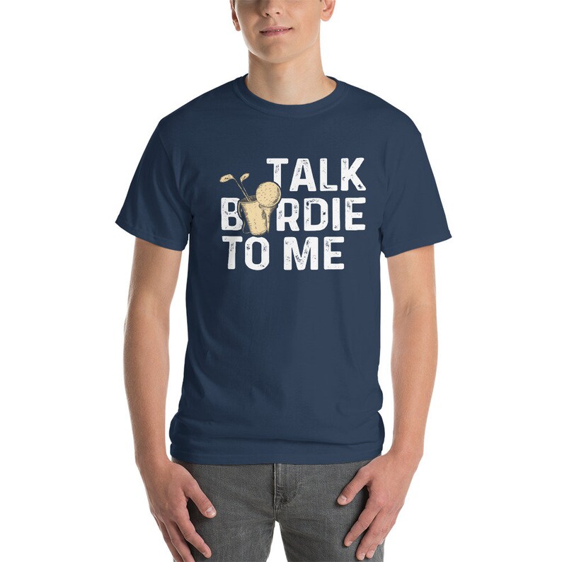 Op de afbeelding: Een marineblauw t-shirt met een witte afbeelding waarop "Talk Birdie To Me" staat. De afbeelding bevat een cartoon van een golfbal in een glas met een rietje.