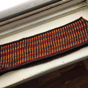 May include: A brown knitted headband with orange, red, and blue stripes.