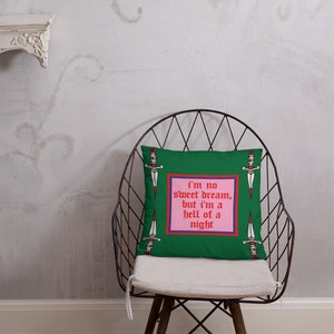 May include: Green decorative pillow with a pink and red framed text that reads "I'm no sweet dream, but I'm a hell of a night." The pillow also features dagger illustrations.