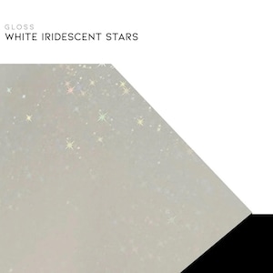 K&ouml;nnte beinhalten: Gl&auml;nzende wei&szlig;e Oberfl&auml;che mit schillerndem sternf&ouml;rmigem Glitzer. Der Text "WHITE IRIDESCENT STARS" wird &uuml;ber der Oberfl&auml;che angezeigt. Der Hintergrund ist wei&szlig; mit einer schwarzen Ecke.