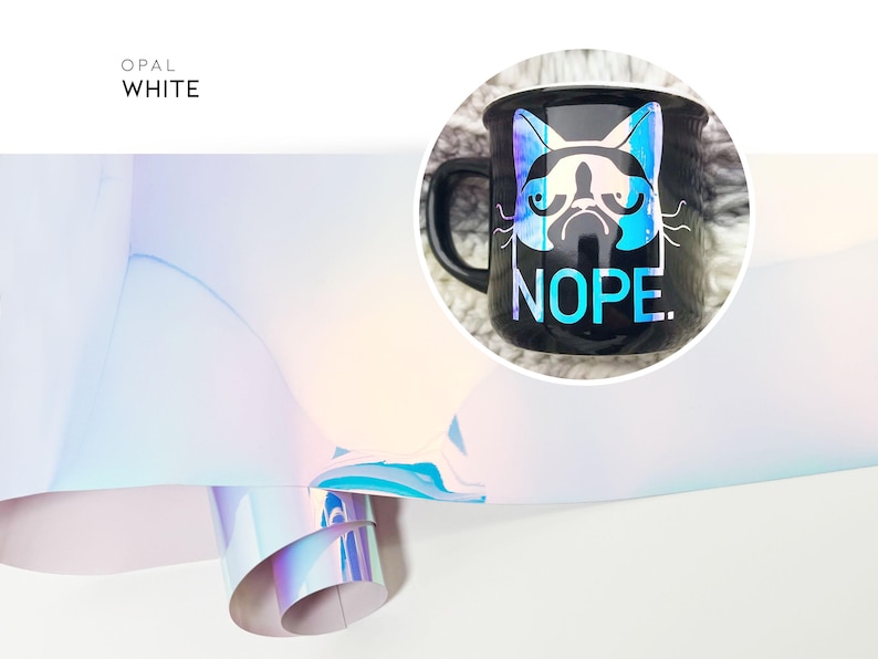 May include: A black ceramic mug with a white cat graphic and the word "NOPE" in blue iridescent vinyl. The mug is sitting on a white surface with a roll of iridescent vinyl in the background.