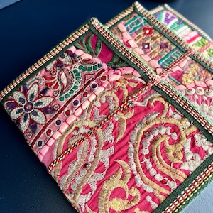 以下が含まれることがあります： 3つの正方形の刺繍コースターのクローズアップ。コースターは、ピンク、ゴールド、グリーン、その他のカラフルな糸とビーズを鮮やかに組み合わせています。エッジは緑色のボーダーと装飾的なステッチでトリミングされています。コースターはおそらく手作りです。