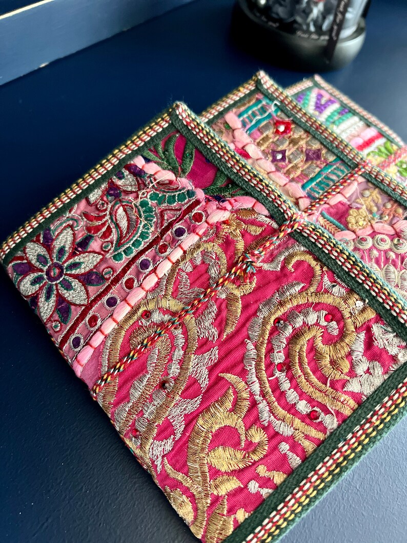 以下が含まれることがあります： 3つの正方形の刺繍コースターのクローズアップ。コースターは、ピンク、ゴールド、グリーン、その他のカラフルな糸とビーズを鮮やかに組み合わせています。エッジは緑色のボーダーと装飾的なステッチでトリミングされています。コースターはおそらく手作りです。
