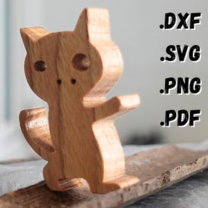 Op de afbeelding: Houten kattenfiguur met een eenvoudig ontwerp, staand op een houten oppervlak. De kat heeft een rond lichaam en een lange staart. Het figuur is gemaakt van lichtbruin hout.