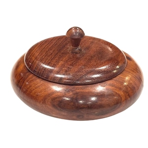May include: A round, wooden container with a lid. The container and lid are a rich, dark brown color with a glossy finish. The lid has a small, rounded knob for easy opening. The wood grain is visible throughout.