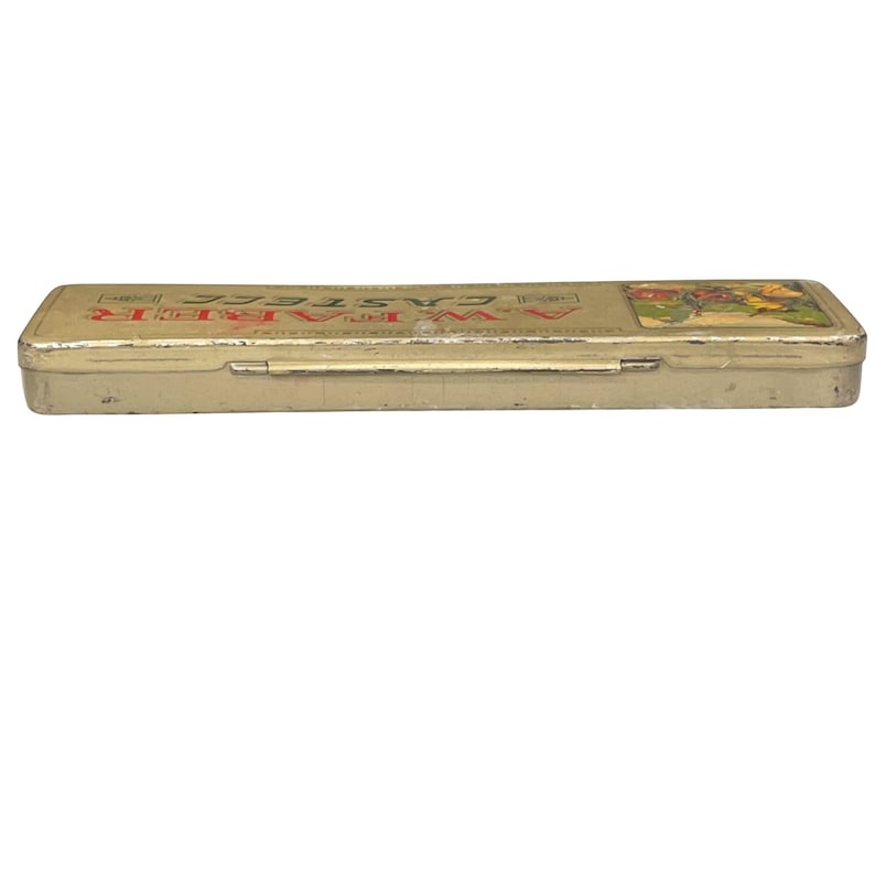 May include: A rectangular, vintage pencil case with a hinged lid. The case is a faded gold colour with the text "A.W. Faber Castell" in red and gold lettering. A colourful illustration is on the right side of the case.