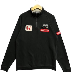 May include: Black long-sleeve sweatshirt with a mock neck and a quarter-zip closure. Features a Honda logo patch, the text "MUGEN POWER", and a "LOCTITE" patch. The sweatshirt has a red and white logo patch on the sleeve.