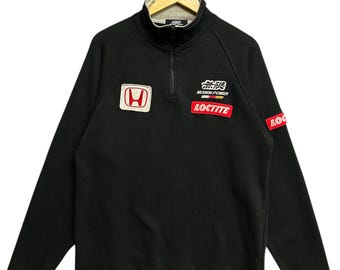 May include: Black long-sleeved sweatshirt with a mock neck and a quarter-zip. It features a Honda logo patch, the text "MUGEN POWER", and a "LOCTITE" patch. The sleeve has a red and white logo patch.