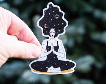 May include: A sticker featuring a woman meditating with a starry night sky for hair. The woman is wearing a black outfit with gold accents and has a crescent moon and star above her head.