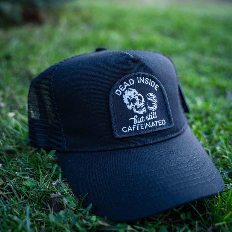 May include: Black trucker hat with a white patch that says "Dead Inside but still caffeinated" and features a skull holding a can.