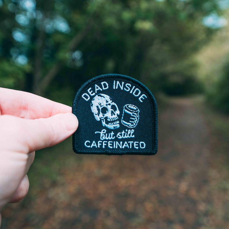 May include: Black embroidered patch with a white skull holding a coffee cup and the text "Dead Inside but still Caffeinated".