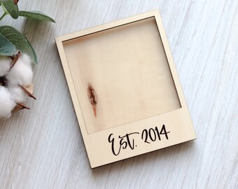 May include: A wooden photo frame with a blank space for a photo and the text "Est. 2014" printed on the bottom.