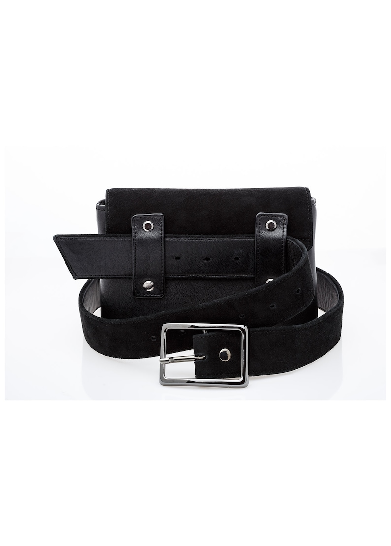 May include: Black suede belt bag with a silver buckle and a black leather strap. The bag has two pockets and a flap closure.