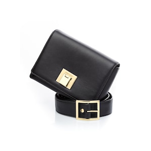 May include: A black leather belt with a gold buckle and a black leather wallet with a gold clasp that says "Ann Demeulemeester".