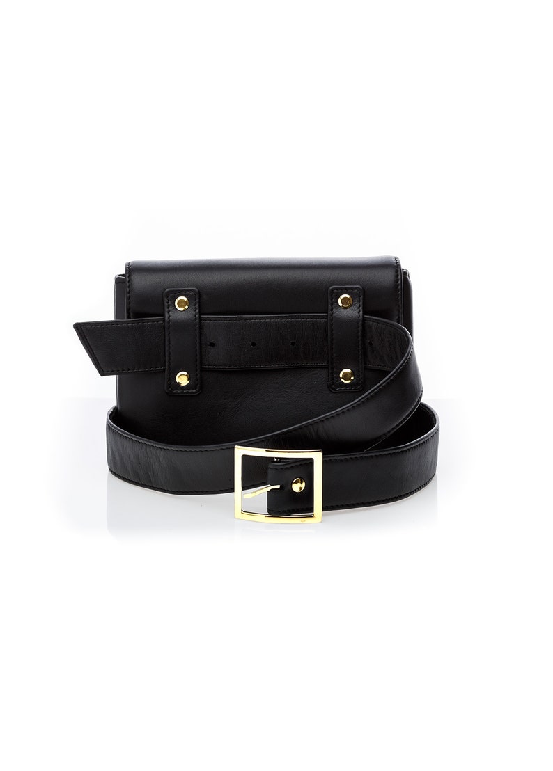 May include: Black leather belt bag with a gold buckle and a detachable strap. The bag has a flap closure and a small pocket on the back.