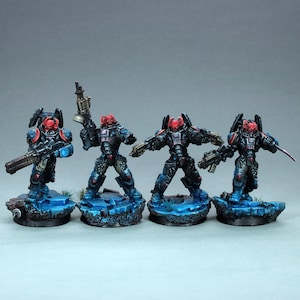 Puede incluir: Cuatro figuras en miniatura negras y azules con cascos rojos y armas. Las figuras están de pie sobre bases azules con una textura rocosa.