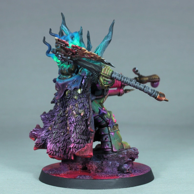May include: A miniature figurine of a fantasy character, painted with vibrant colors. The figure is posed with a weapon, wearing armor and a cloak. The color palette includes shades of green, purple, blue, and pink, with intricate detailing.