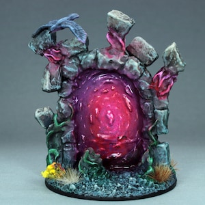 May include: A miniature stone archway with a glowing pink portal, surrounded by green vines and a small bird perched on top. The base is covered in blue and gray stones.