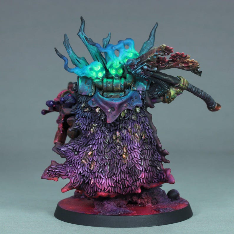 May include: A miniature figurine of a fantasy character, featuring a detailed paint job with vibrant colors. The figure has a purple and blue cloak, a weapon, and a base with a red and purple color scheme. The figure has a helmet with blue and green accents.