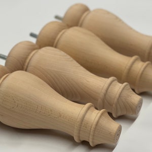 May include: Four unfinished wooden furniture legs with a turned design and a metal screw at the bottom.