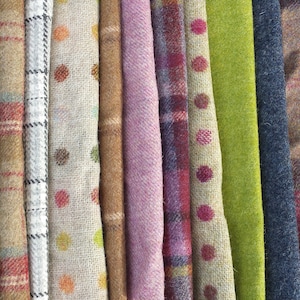 May include: A collection of fabric swatches in various colours and patterns, including plaid, polka dots, and stripes. The fabrics are all woven and have a textured appearance.