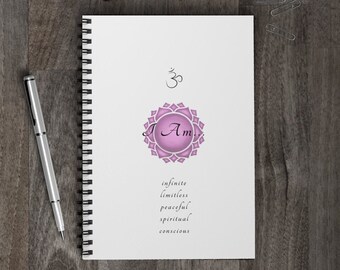 Könnte beinhalten: Ein weißes Spiralnotizbuch mit einem rosa und weißen Mandala-Design und den Worten "Ich Bin" in kursiver Schrift. Die Worte "unendlich, grenzenlos, friedlich, spirituell, bewusst" sind unter dem Mandala gedruckt. Das Notizbuch hat oben ein schwarz-weißes Om-Symbol.