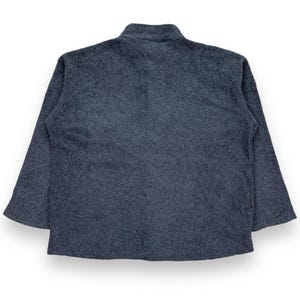 May include: A dark gray fleece jacket with a high collar and long sleeves. The jacket has a soft, textured appearance and a relaxed fit. The back view of the jacket is shown against a white background.