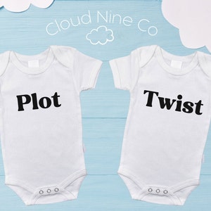 Peut inclure: Deux bodies blancs pour bébé à manches courtes. Les bodies ont un texte noir. Un body dit "Plot" et l'autre dit "Twist".