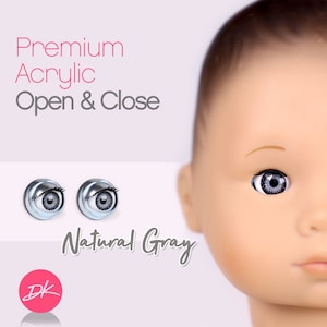 Peut inclure: Deux yeux de poupée en acrylique gris avec des pupilles noires. Les yeux s'ouvrent et se ferment. Le texte "Premium Acrylic Open & Close Natural Gray" est sous les yeux. Le texte "DK" est dans un cercle rose sous le texte.