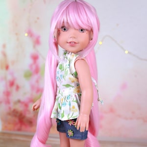 Può includere: Bambola con lunghi capelli rosa, che indossa un top floreale, pantaloncini di jeans con applicazioni floreali e scarpe da ginnastica alte bianche. La bambola ha ombretto rosa e orecchini. Lo sfondo è un motivo floreale sfocato.