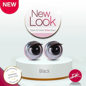 May include: Two black open and close glass eyes with eyelashes, displayed on a white pedestal. The text "New Look" and "Open & Close Glass Eyes" are visible. The word "Black" is also displayed.