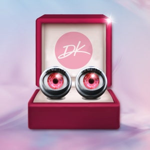 May include: A red velvet box with a pink circle containing the letters "DK" in white. The box contains two silver-colored eyeballs with pink irises.