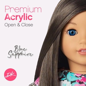 Peut inclure: Une poupée aux longs cheveux bruns et aux yeux bleus. La poupée porte une robe à imprimé floral. Le texte "Premium Acrylic Open & Close" est en lettres roses en haut de l'image. Le texte "Blue Sapphire" est en lettres grises en bas de l'image. Le texte "DK" est en lettres roses dans un cercle en bas de l'image.