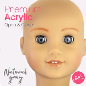 May include: Close-up of a doll's face with gray acrylic eyes. The doll's eyes are open and the doll has a light peach complexion. The text "Premium Acrylic Open & Close" is in the upper left corner of the image. The text "Natural gray" is in the lower left corner of the image. The text "DK" is in a pink circle in the lower right corner of the image.