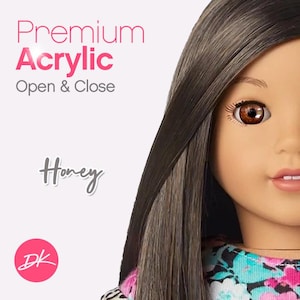 Peut inclure: Gros plan sur le visage d'une poupée avec de longs cheveux bruns. La poupée a les yeux bruns et porte une chemise à imprimé floral. Le texte "Premium Acrylic Open & Close Honey" est visible en arrière-plan.