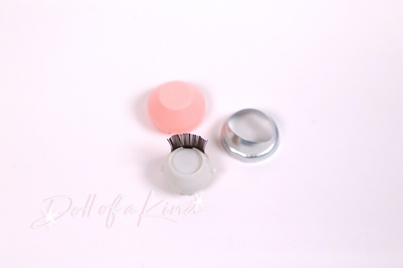 May include: Three eyelash application tools. A white tool with a black lash strip, a pink silicone tool, and a silver metal ring.