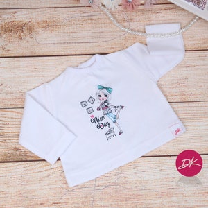 May include: White long-sleeve shirt with a graphic of a girl holding a shopping cart and the text "Nice Day".