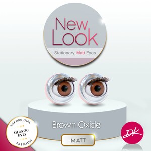 May include: Two brown plastic doll eyes with a silver rim and black eyelashes. The eyes are on a white platform with the text "New Look Stationary Matt Eyes" and "Brown Oxide MATT" in a circle. The text "The Original Glastic Eyes Premium" is in a circle with stars. The text "DK" is in a circle with a pink background.
