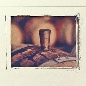 May include: A close-up of a wooden barrel with a metal top. The barrel is brown and has a rough texture. The metal top is silver and has a smooth texture.